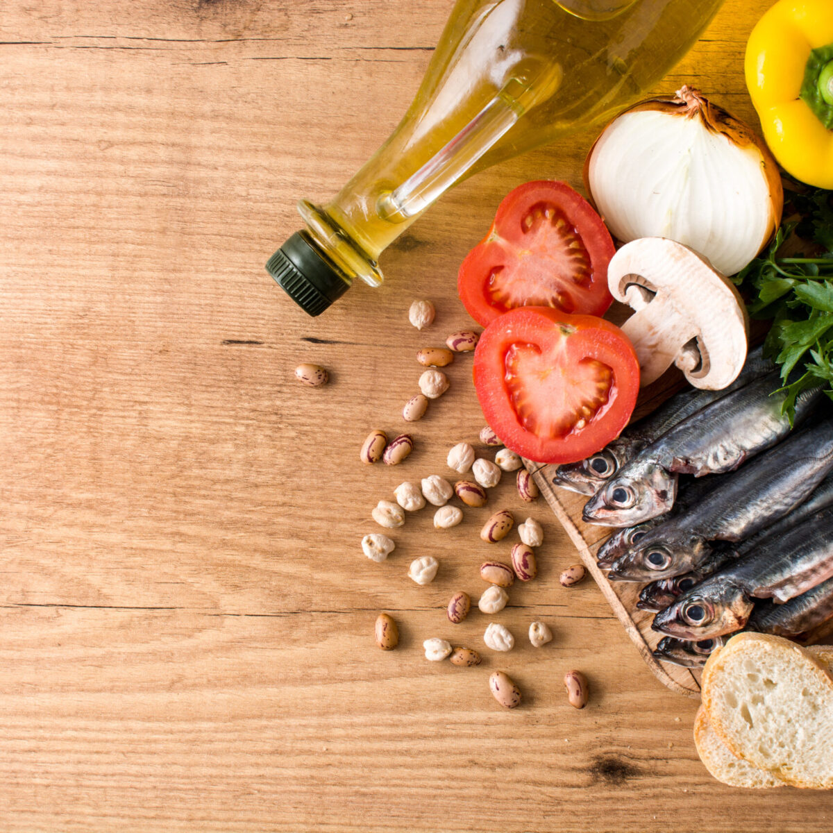 Fresh sardines, tomatoes, onion, bell peppers, parsley, olive oil, beans, mushroom, apple and bread composing a healthy mediterranean diet